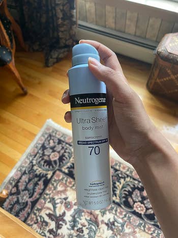 Reviewer holding Neutrogena sunscreen can