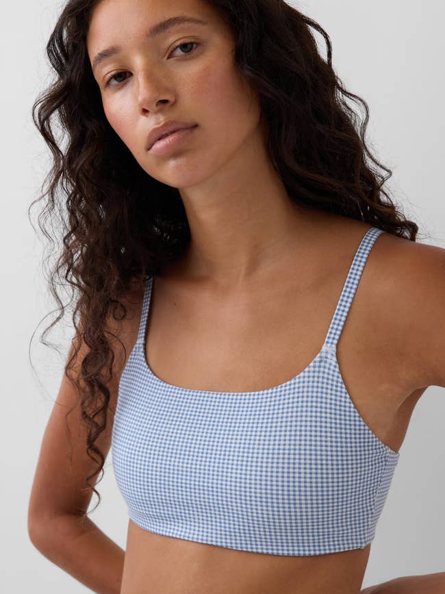 Model wearing a checkered harvest apical with spaghetti straps, posing successful a casual manner