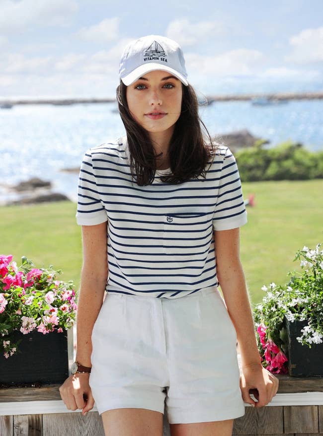 Model is wearing the white linen shorts with a white and navy blue striped tee and white cap