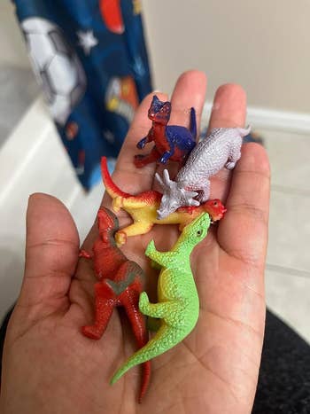 A reviewer's hand holding the dino toys
