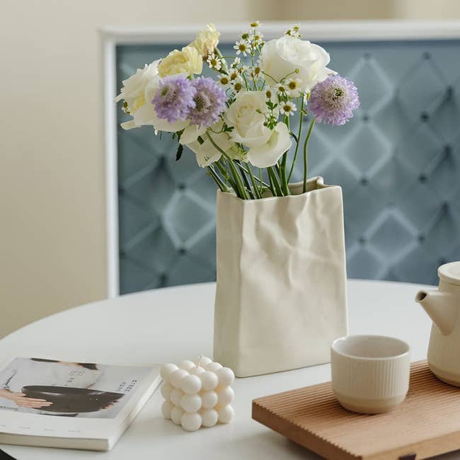 An off-white insubstantial container shaped vase with flowers successful it