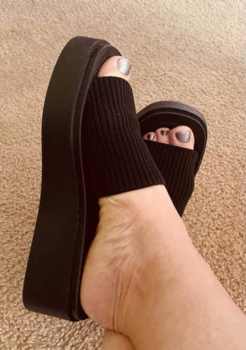 Person wearing achromatic level sandals with heavy soles and metallic nail polish connected toes
