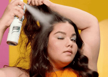 gif of a model spraying dry shampoo into different sections of their hair