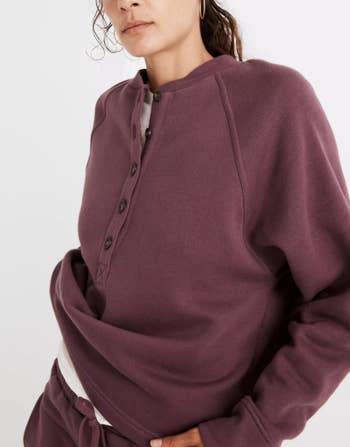 a model in a burgundy slouchy sweatshirt with buttons half way down