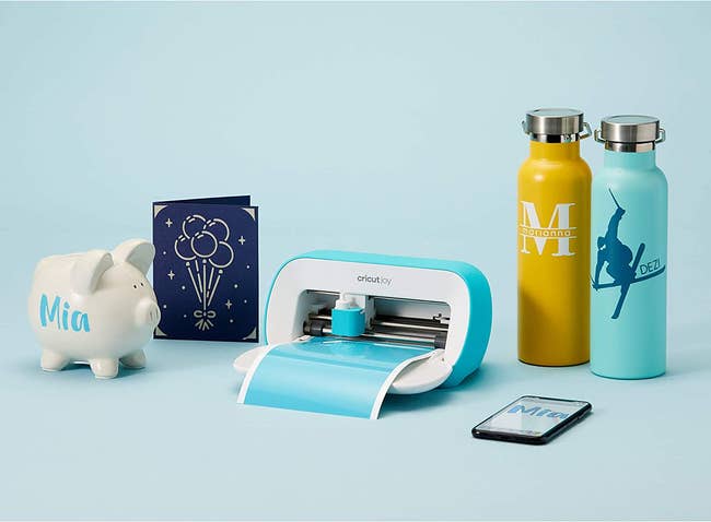 a small blue cricut joy machine surrounded by objects with customized decals