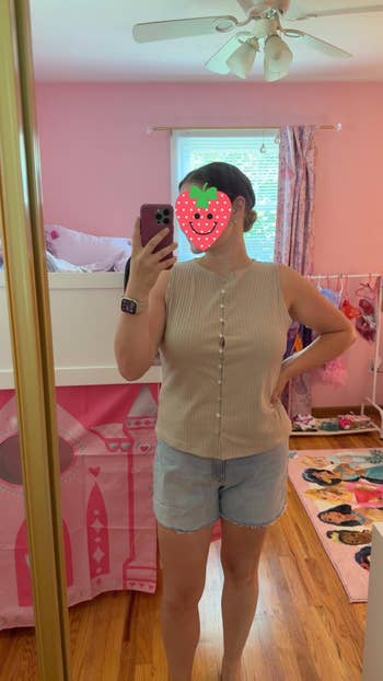 Person taking a reflector  selfie wearing a ribbed sleeveless apical  and denim shorts, lasting  successful  a pink-themed country   with a child's play   tent