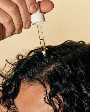 a closeup of the oil being put on curly hair