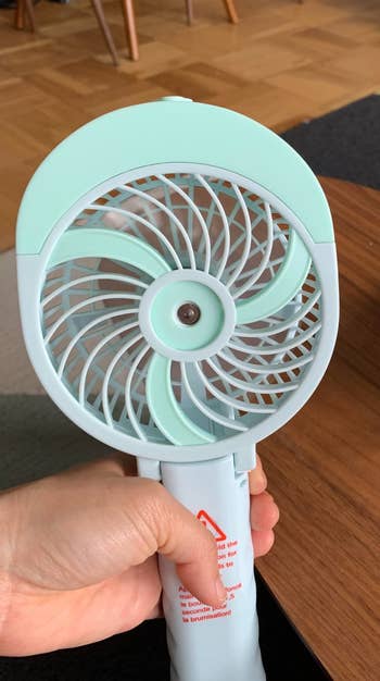 reviewer holding handheld fan