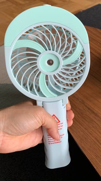 reviewer holding handheld fan