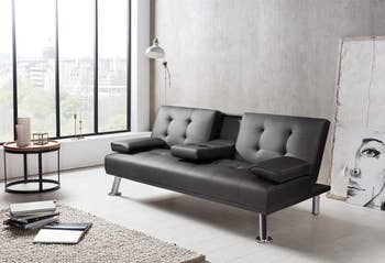 the black faux leather futon with the middle piece pulled down to reveal cupholders