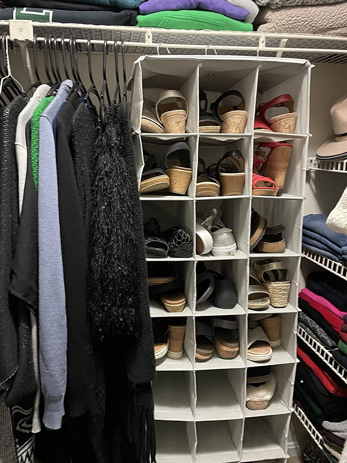 reviewer image of the hanging shoe organizer hanging in a closet with shoes in most of the 24 compartments
