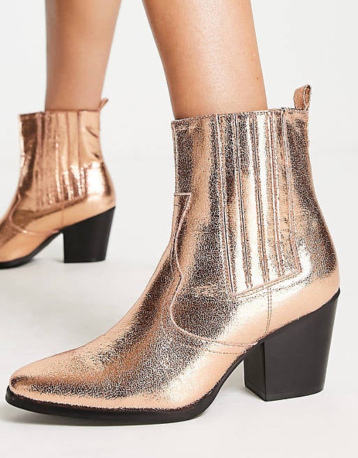 model in gold bronze booties with black low-medium chunky heel