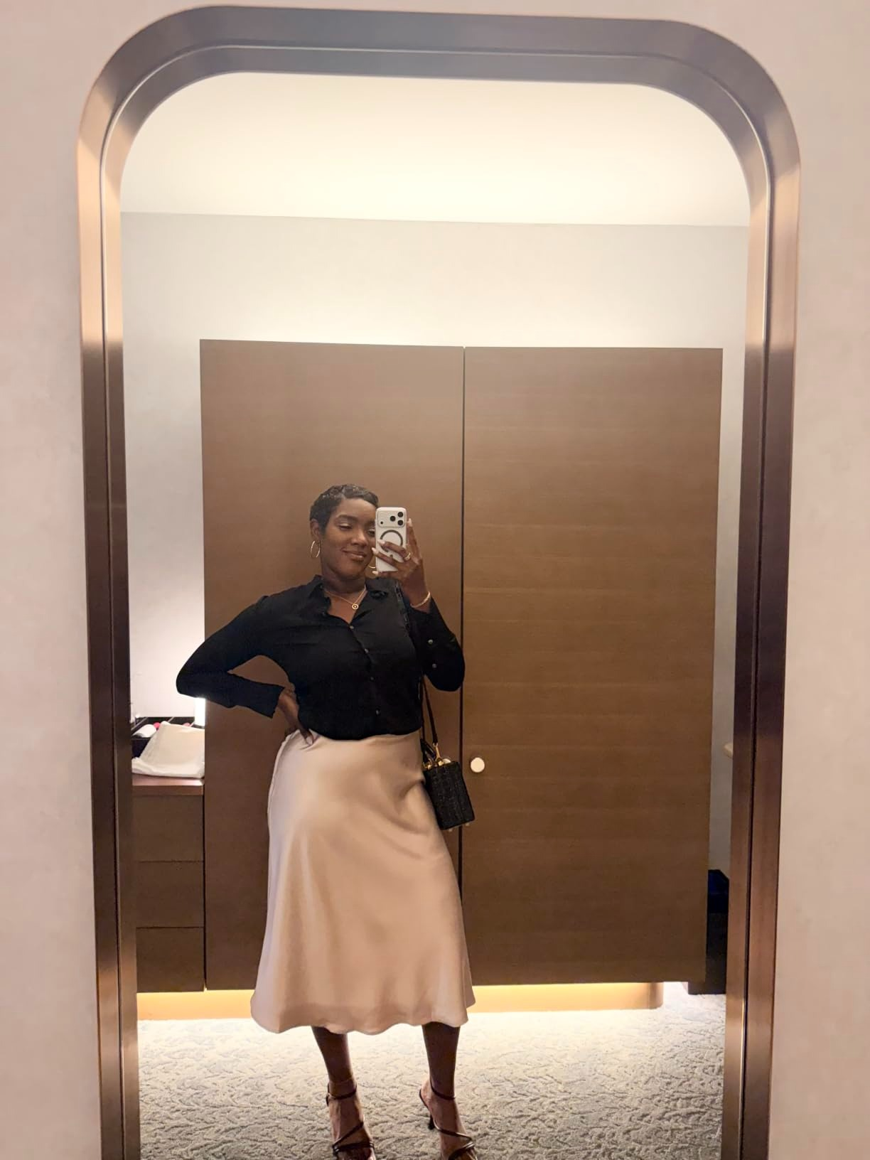 Person taking a reflector  selfie, wearing a stylish achromatic  blouse and airy  skirt, accessorized with a tiny  handbag