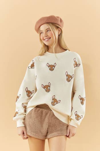 a model in a cream colored sweatshirt with bambi embroidered on it