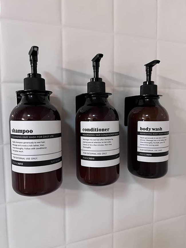 Reviewer's shampoo, conditioner, and body wash bottles are shown on the wall of a shower