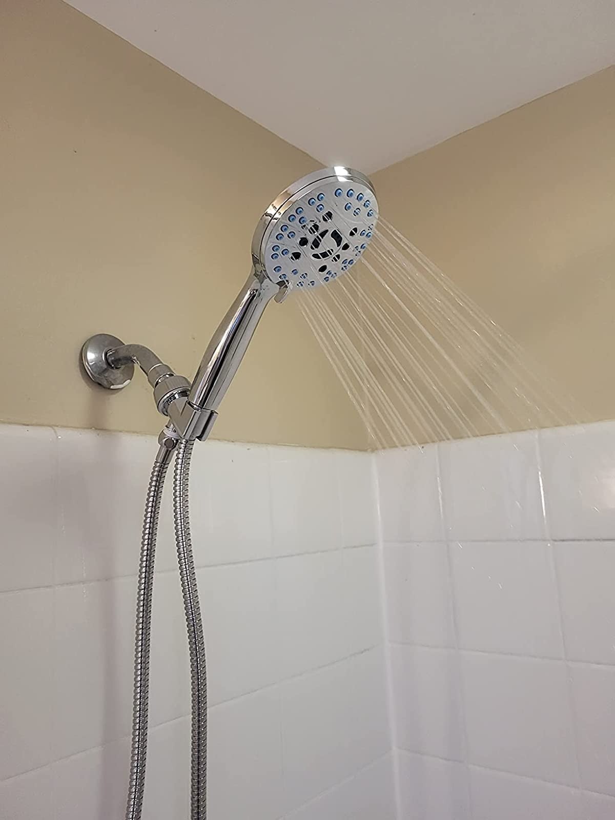reviewer image of the shower head installed in a shower, streaming water
