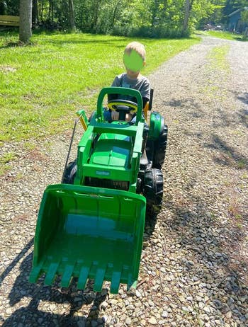 a child on a Peg Perego John Deere Ground Loader Ride On Tractor 