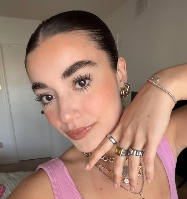 Person successful a sleeveless apical showing jewelry and makeup, posing indoors