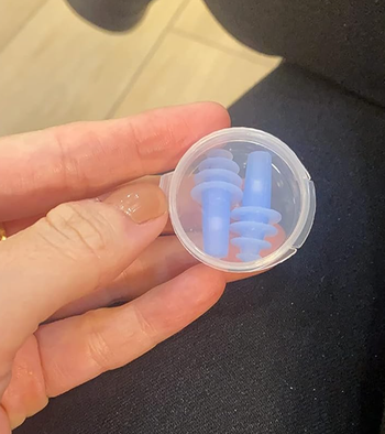 Reviewer holding case with small blue spiraling earplugs 