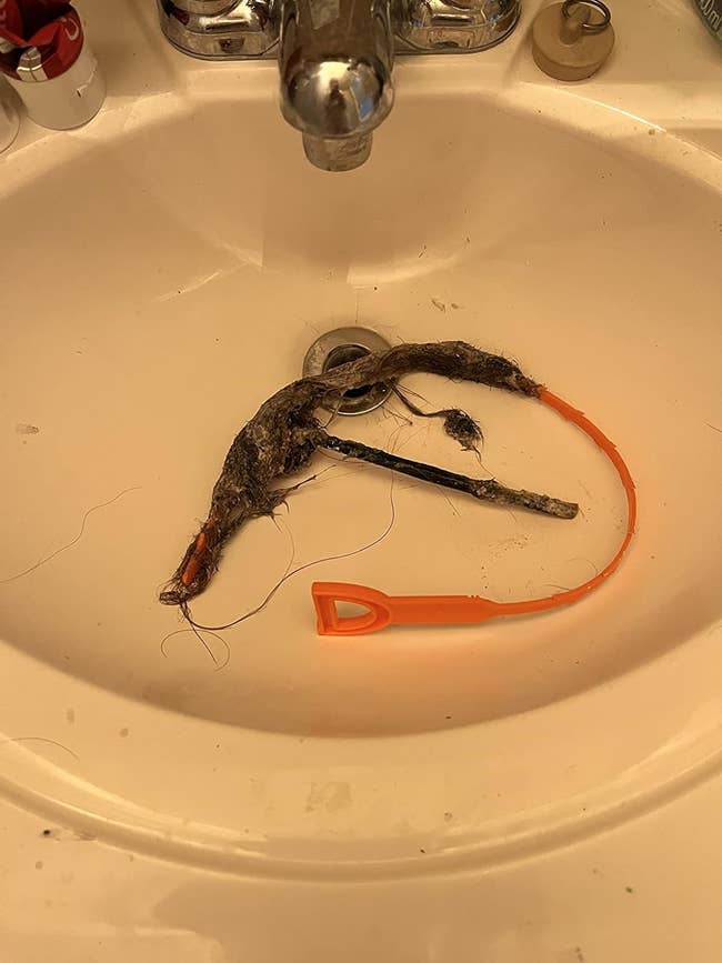a reviewer's orange snack in their sink with a ton of hair on them