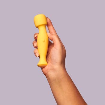 Hand holding yellow mini wand vibrator