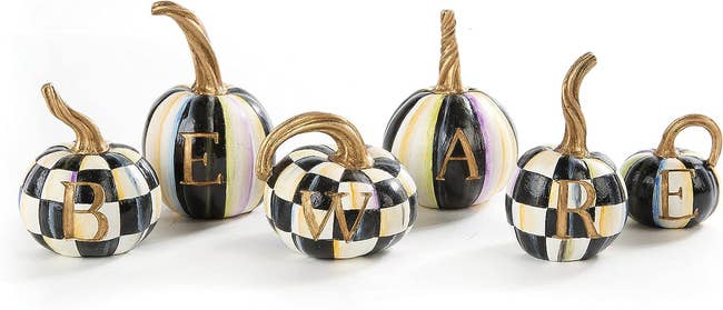 Black, white, and gold pumpkins each with a letter that spells out 