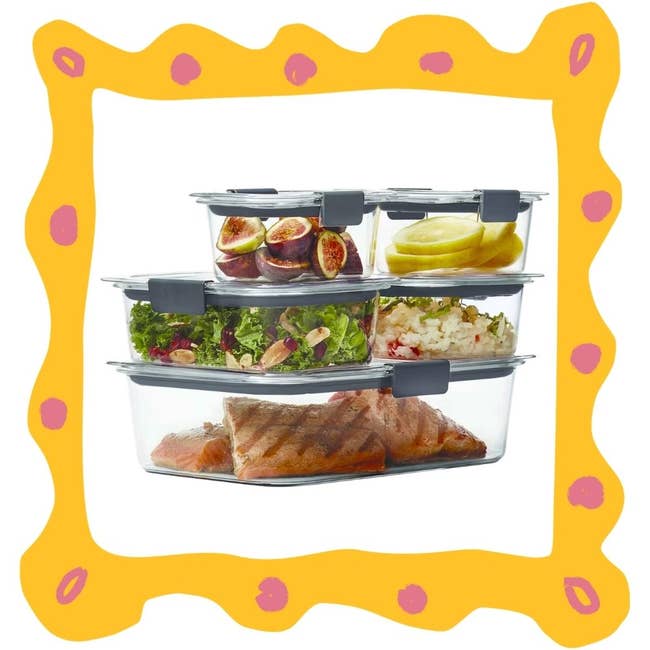 Stacked glass food containers filled with figs, apple slices, salad, mashed potatoes, and grilled salmon
