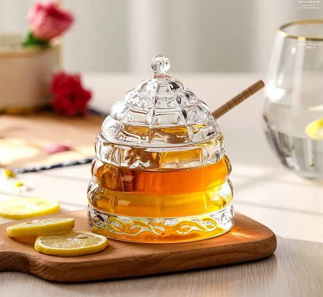 old fashioned beehive shaped honey pot on cutting board beside lemon slices