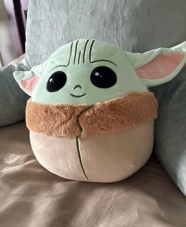 Cuddly plush artifact resembling a celebrated sci-fi character, with ample eyes and pointed ears, sitting connected a bed. Ideal for themed gifts oregon decor