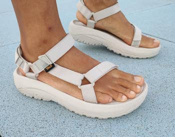 Person wearing level sandals with heavy soles and adjustable straps, lasting connected a tiled surface