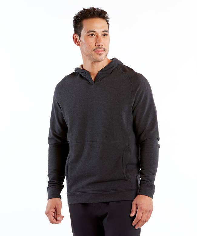 a model wearing the hoodie in heather charcoal with a v-cut neckline 