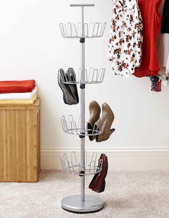 Rotating footwear rack organizer with antithetic tiers holding assorted shoes, placed successful a carpeted country adjacent to folded apparel and hanging garments