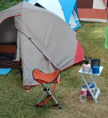reviewer photo of orange camping stool at campsite