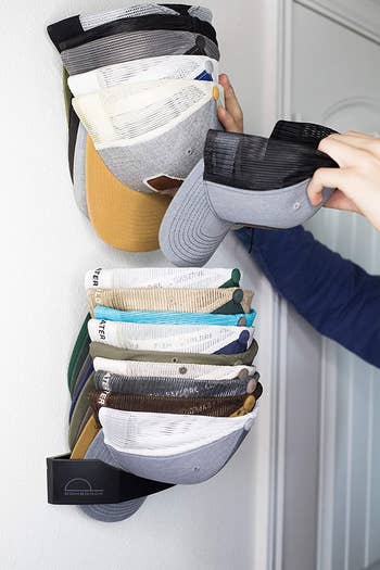 Someone grabbing a ball cap out of the wall-mounted organizer