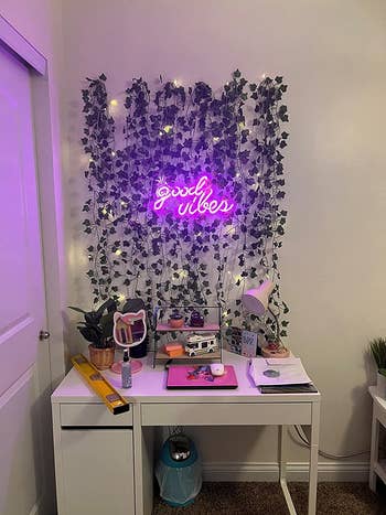 The neon sign above a desk on a wall with artificial vines