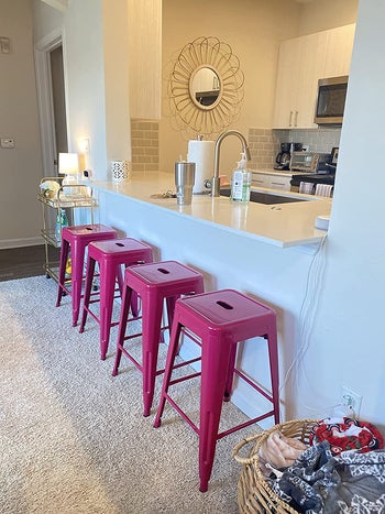 a set of four hot pink metal stools in a row
