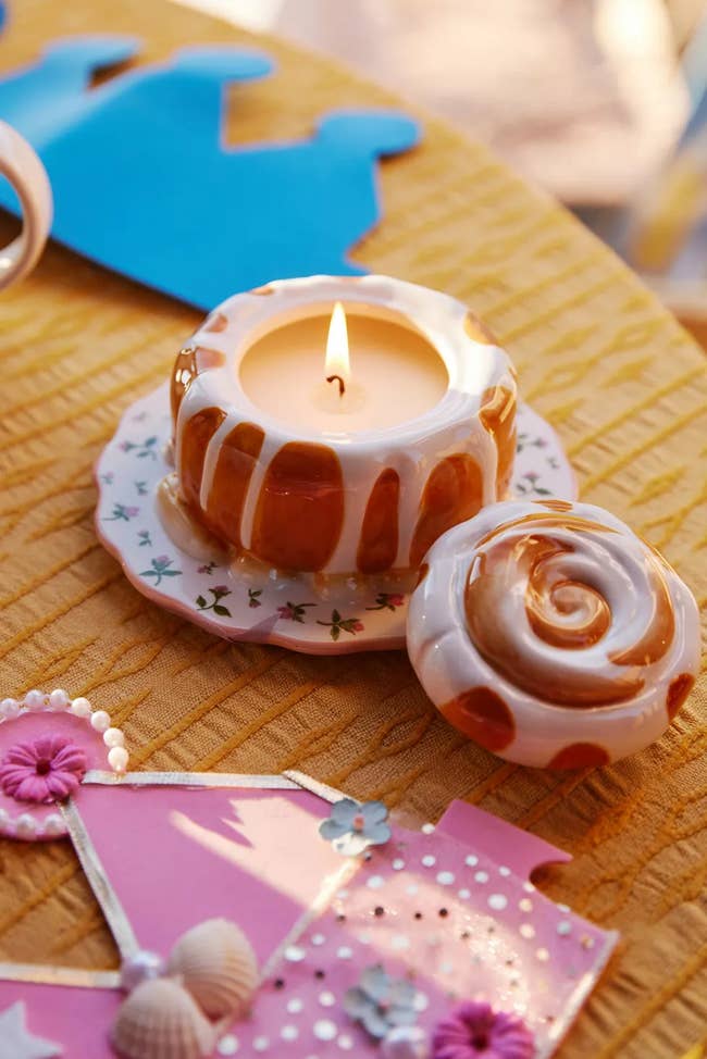 Candle shaped similar  a bundt barroom   lit connected  a decorative plate, with a matching lid adjacent    connected  a array  adorned with crafts and shells