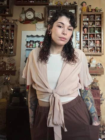 Person with tattoos wearing a tied-front top and wide-leg pants