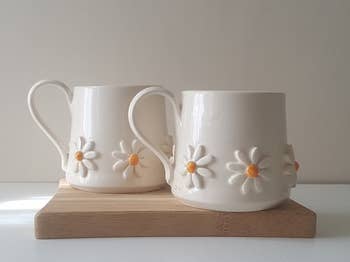 two white mugs with 3d daisies around the base