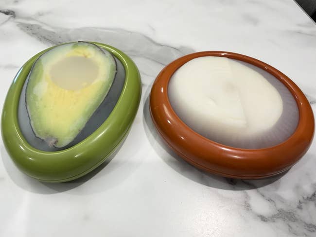Two integrative  nutrient  savers shaped similar  fractional  avocado and onion, placed connected  a marble countertop