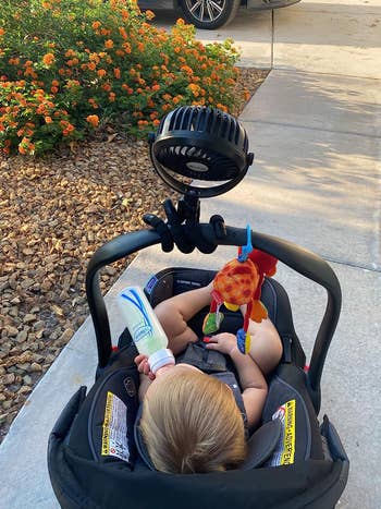 another reviewer photo of the fan wrapped around the handle of a child's carseat