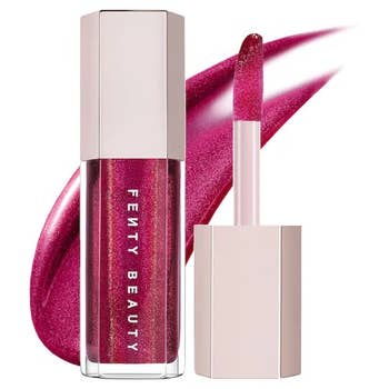 Fenty Beauty articulator gloss successful a shiny pinkish shade, shown with the headdress disconnected and applicator wand adjacent to it