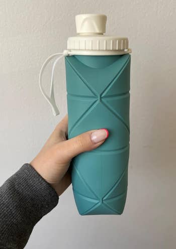 a hand holding up the collapsible water bottle