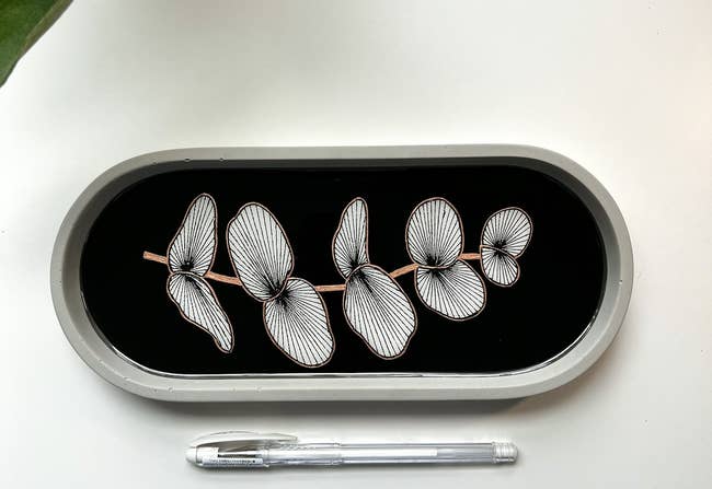 Silver orchid-shaped jewelry set in a display case with a pen for scale. Perfect for accessorizing