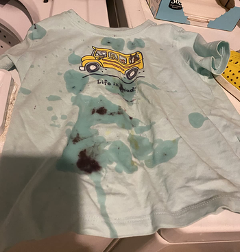 a reviewer photo of a child's shirt covered in dark stains
