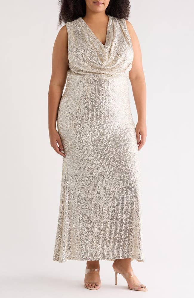 Person modeling a floor-length, sleeveless sequined gown with a draped neckline, suitable for formal events or occasions