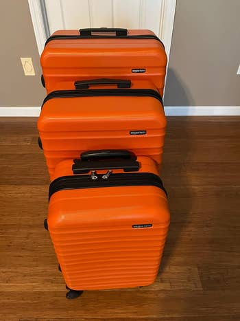 three orangish  rolling suitcases successful  antithetic  sizes