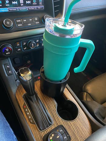 reviewer's teal 40-oz tumbler in the car cup holder using the extender