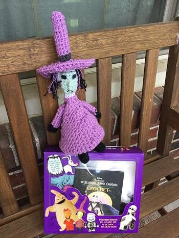 Crochet witch doll styled with chapeau  and formal  connected  a bench. Nearby is simply a crochet acquisition   kit with Halloween-themed designs