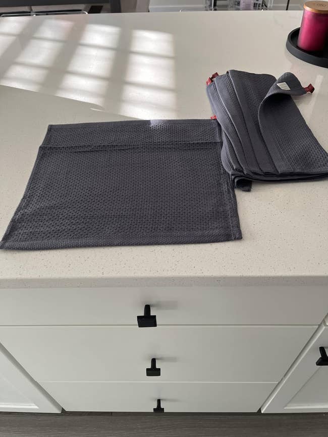 Dark room  towels are displayed connected  a achromatic  countertop, with 1  towel laid level  and others folded beside it